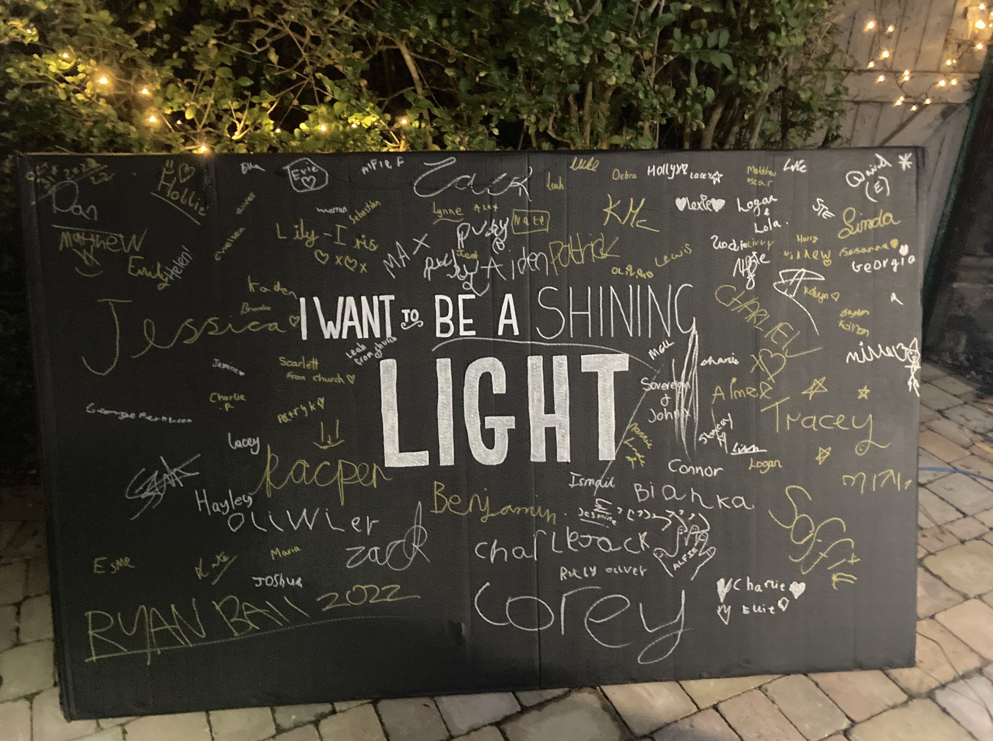 A large surface emblazoned I want to be a shining light, and signed by dozens of people in glitter pen